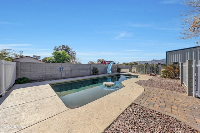 view of pool featuring a water slide, a mountain view, and a patio area