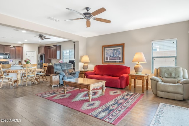 living room with ceiling fan, sink, and light wood-type flooring