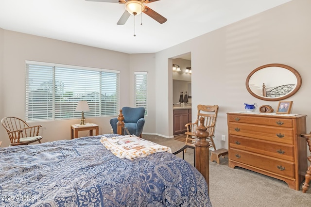 bedroom with ceiling fan, light colored carpet, and ensuite bath