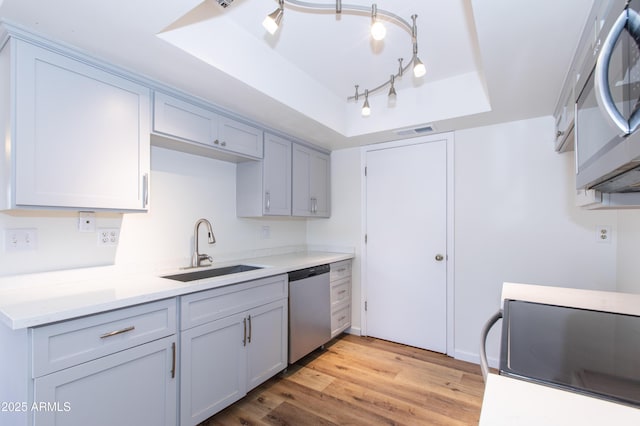 222 W Brown Rd Unit 72, Mesa, AZ 85201 - kitchen featuring stainless steel appliances, a sink, a tray ceiling, light wood-style flooring, and light countertops