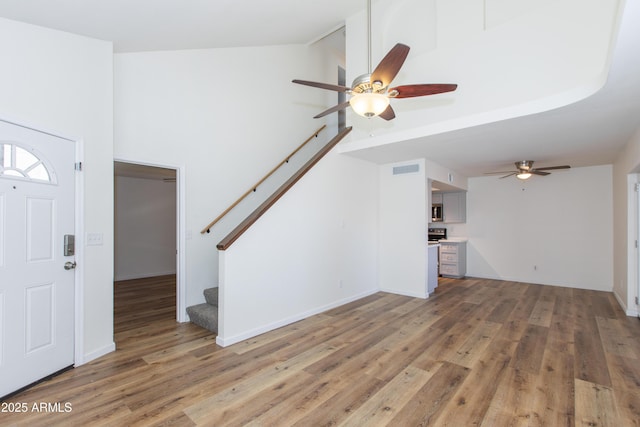 222 W Brown Rd Unit 72, Mesa, AZ 85201 - unfurnished living room featuring ceiling fan, stairway, light wood finished floors, and a high ceiling