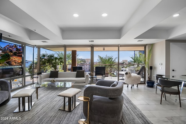 tiled living room featuring a wall of windows, a healthy amount of sunlight, and a raised ceiling