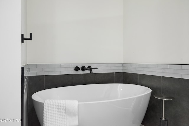 bathroom with tile walls and a bathtub