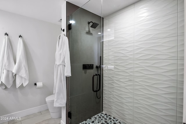 bathroom featuring toilet, a shower with shower door, and tile patterned floors