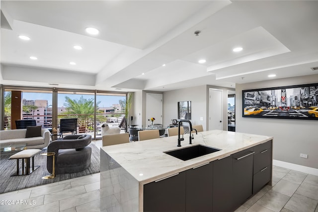 kitchen with a large island, light stone countertops, sink, and light tile patterned floors