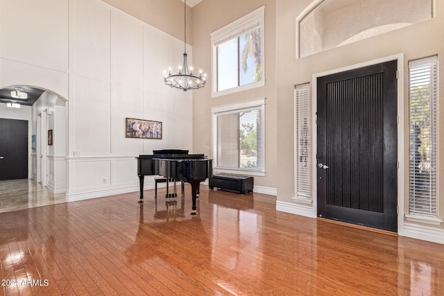 entrance foyer with a towering ceiling, wood-type flooring, and a chandelier