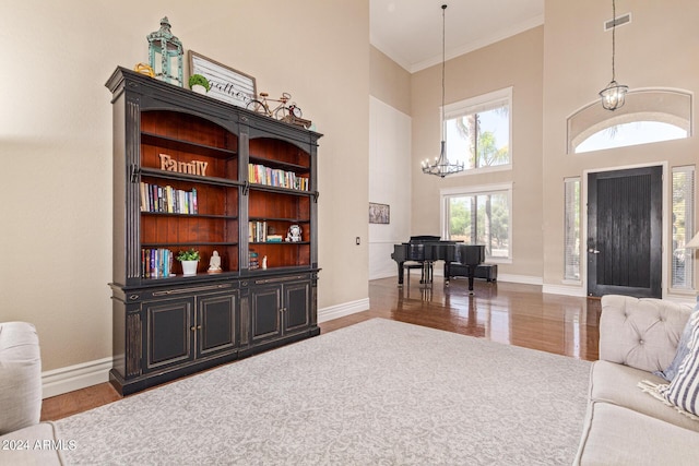 interior space with crown molding, a notable chandelier, a towering ceiling, and dark wood-type flooring