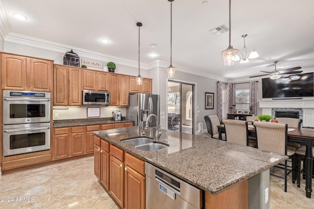 kitchen with stainless steel appliances, an island with sink, hanging light fixtures, and sink