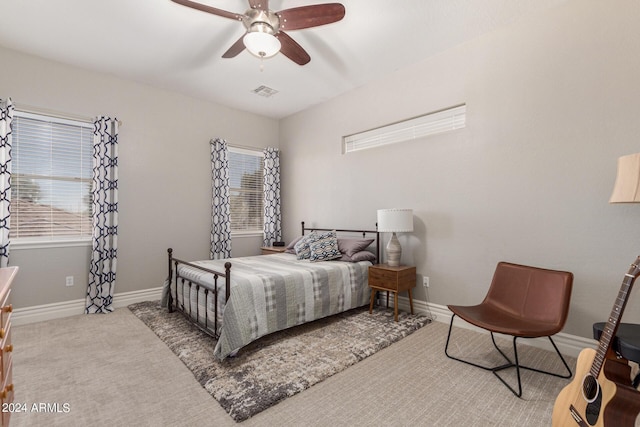 bedroom featuring ceiling fan, multiple windows, and light carpet