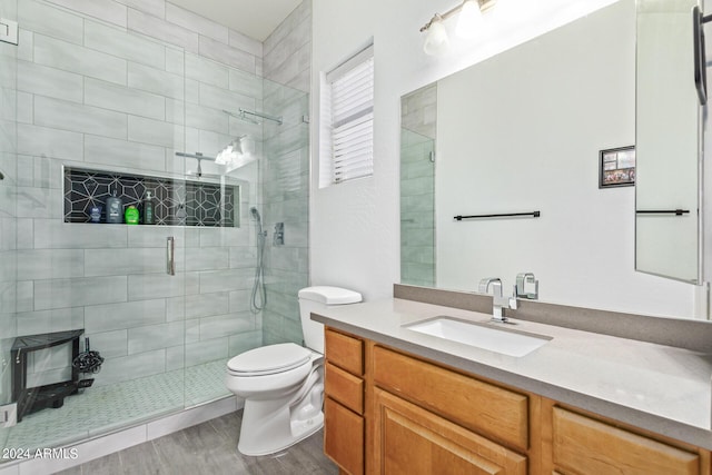 bathroom with vanity, toilet, a shower with shower door, and hardwood / wood-style floors