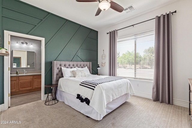 bedroom with ceiling fan, ensuite bathroom, and light carpet