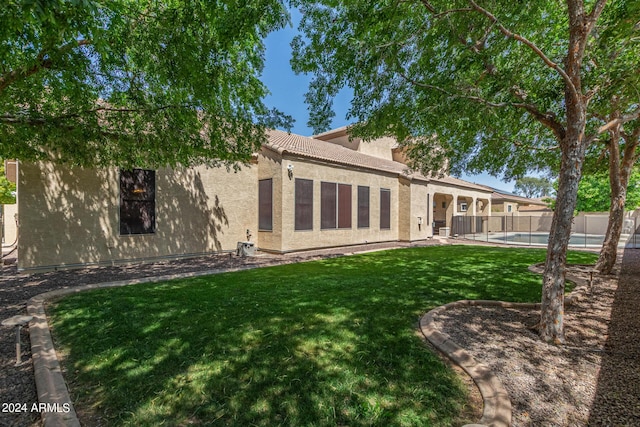 rear view of property featuring a fenced in pool and a yard