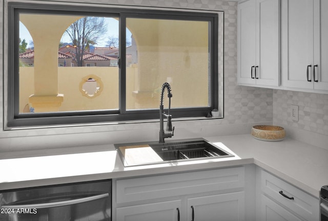 kitchen featuring light countertops, backsplash, white cabinetry, a sink, and dishwasher