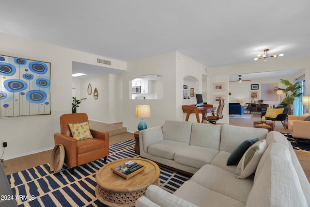 living area featuring arched walkways, visible vents, baseboards, and wood finished floors