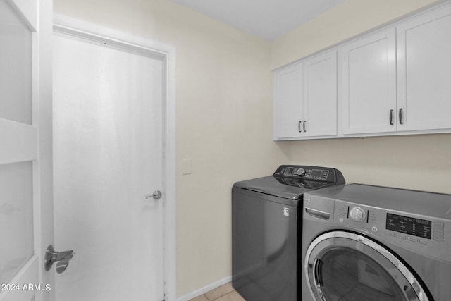 washroom featuring baseboards, cabinet space, washing machine and clothes dryer, and light tile patterned flooring