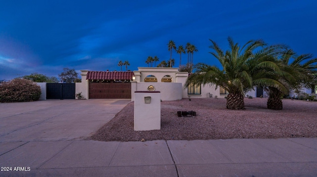 view of front of property featuring stucco siding, a gate, fence, driveway, and a tiled roof