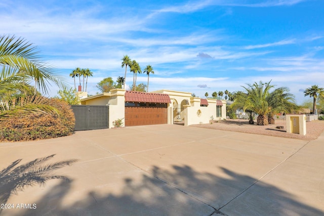 view of front of home featuring a garage, concrete driveway, a tiled roof, a gate, and stucco siding