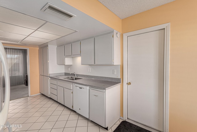 kitchen with white cabinetry, dishwasher, light tile patterned flooring, and sink