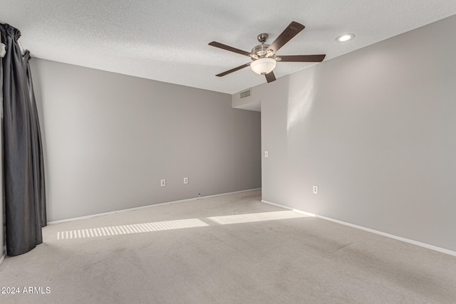 carpeted spare room featuring ceiling fan and a textured ceiling