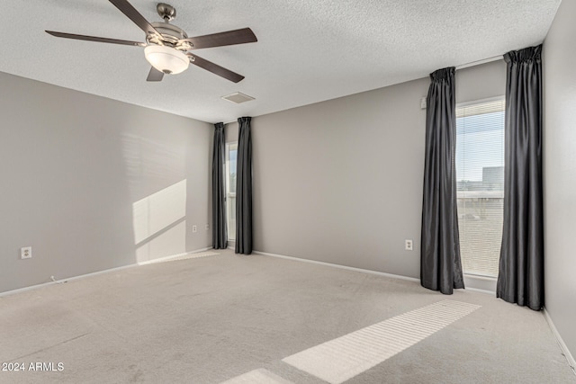 unfurnished room with a textured ceiling, ceiling fan, and light carpet