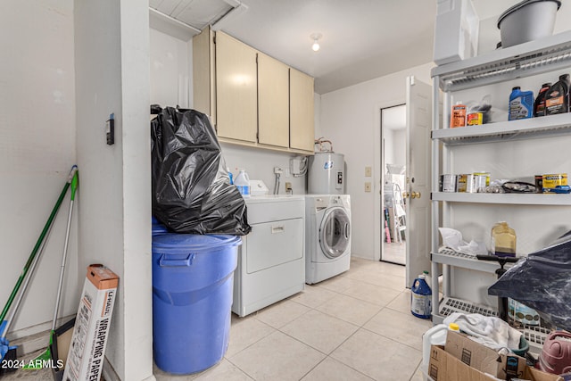 laundry area with washer and clothes dryer, light tile patterned flooring, cabinets, and water heater