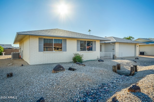 ranch-style home with a garage and central AC unit