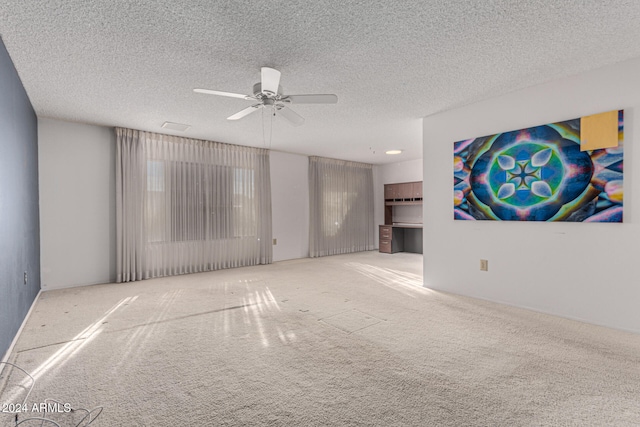 carpeted empty room featuring a textured ceiling and ceiling fan