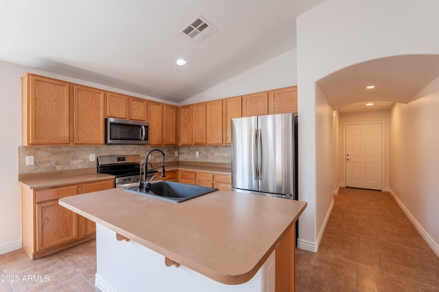 41767 W Somerset Dr, Maricopa, AZ 85138 - kitchen featuring appliances with stainless steel finishes, backsplash, light countertops, lofted ceiling, and arched walkways
