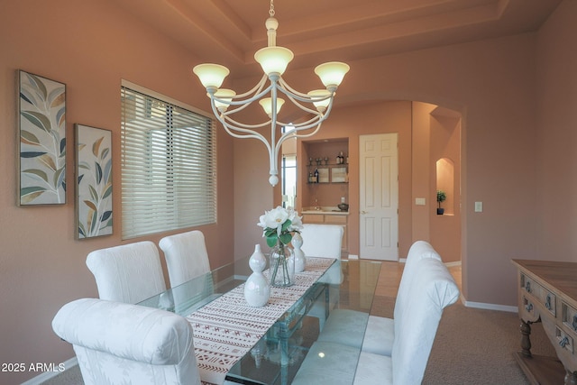 dining area featuring arched walkways, baseboards, a raised ceiling, and an inviting chandelier