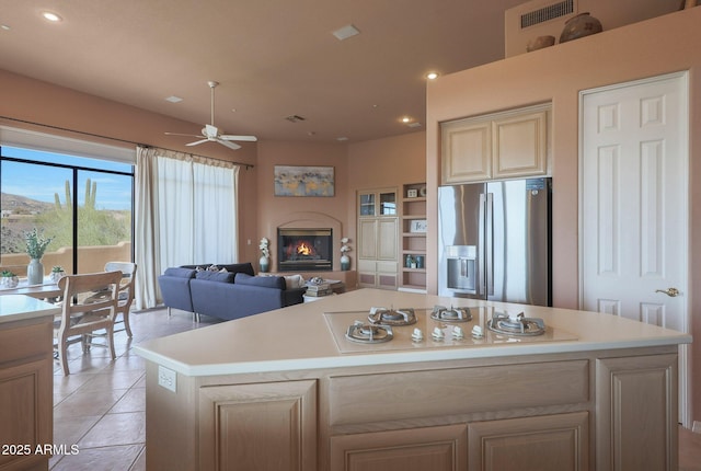 kitchen featuring white gas stovetop, a glass covered fireplace, stainless steel fridge, and light countertops