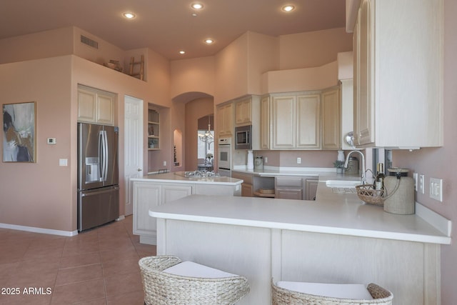 kitchen featuring visible vents, arched walkways, appliances with stainless steel finishes, a sink, and light tile patterned flooring