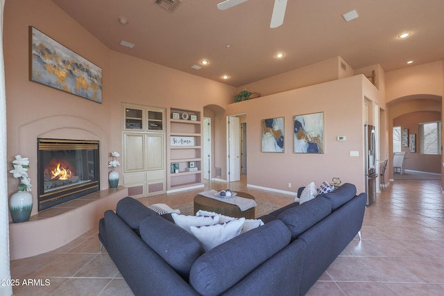 living area featuring light tile patterned floors, visible vents, a premium fireplace, and arched walkways