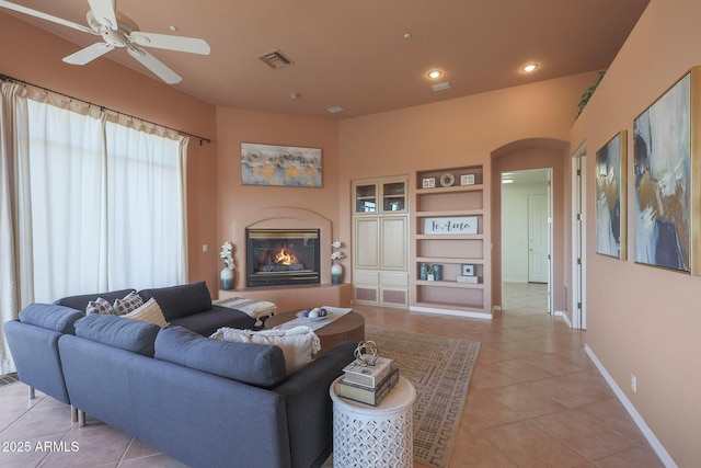 living room with arched walkways, light tile patterned floors, recessed lighting, visible vents, and a glass covered fireplace