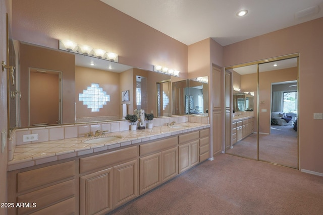 bathroom with double vanity, carpet, baseboards, and a sink