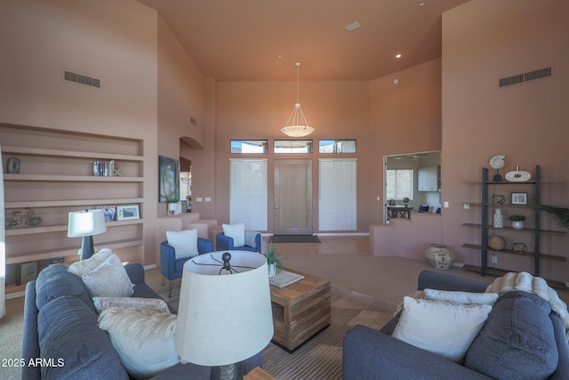 living area with a towering ceiling, visible vents, and built in features