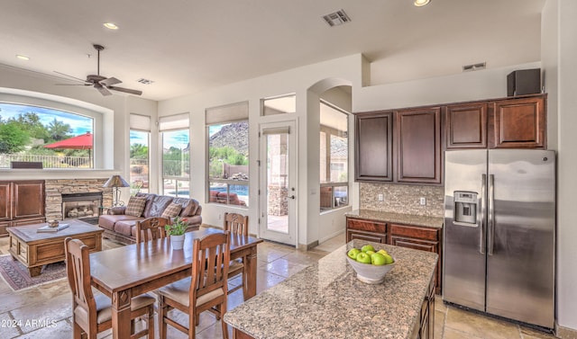 kitchen featuring a center island, stainless steel fridge, a fireplace, light stone countertops, and decorative backsplash