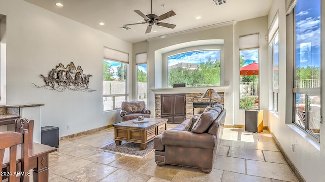 sunroom featuring a stone fireplace and ceiling fan