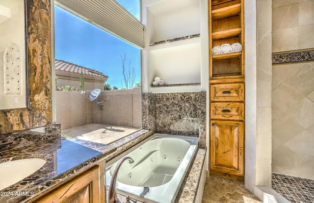 bathroom featuring a relaxing tiled tub and vanity