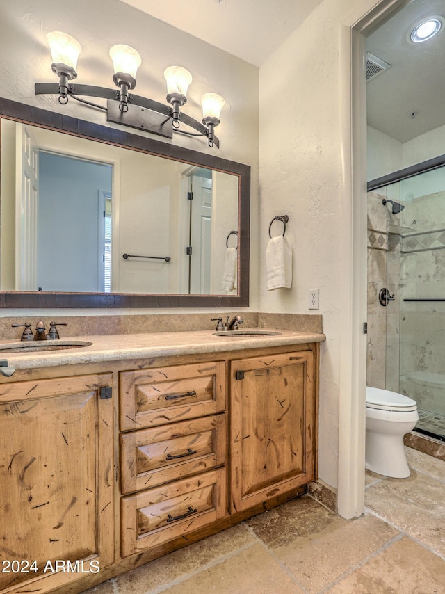 bathroom featuring toilet, vanity, and a shower with shower door