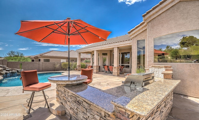 view of patio / terrace with a fenced in pool, pool water feature, a grill, and exterior kitchen