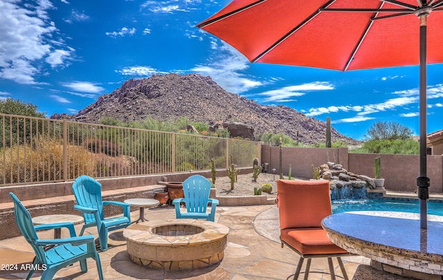 view of patio / terrace featuring pool water feature, an outdoor fire pit, and a mountain view