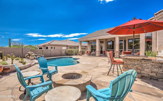 view of swimming pool featuring a bar, an outdoor fire pit, and a patio