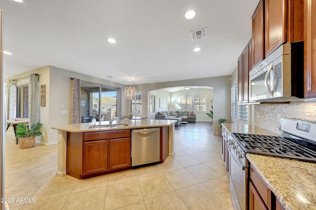 kitchen featuring tasteful backsplash, stainless steel appliances, light stone countertops, and sink