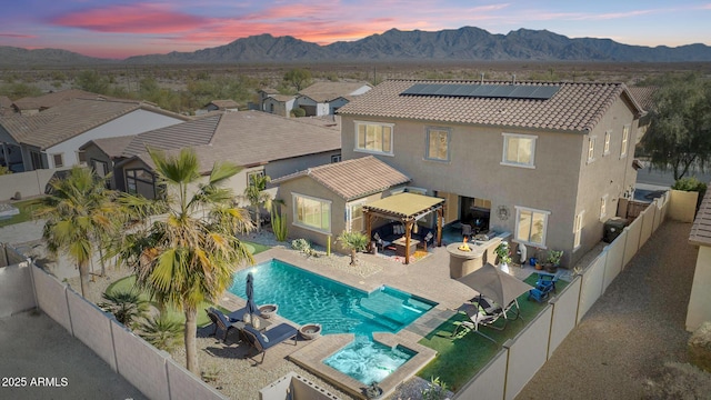 pool at dusk featuring a mountain view and a patio