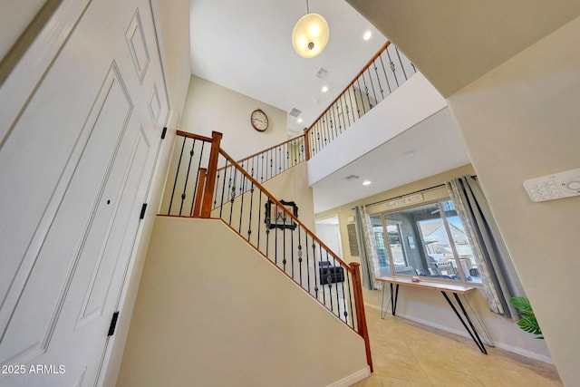 stairway featuring tile patterned floors and a high ceiling