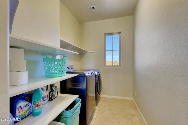 clothes washing area featuring washing machine and dryer and light tile patterned flooring