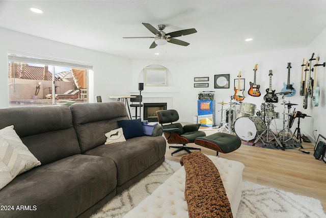 living room with ceiling fan, a fireplace, and light hardwood / wood-style flooring