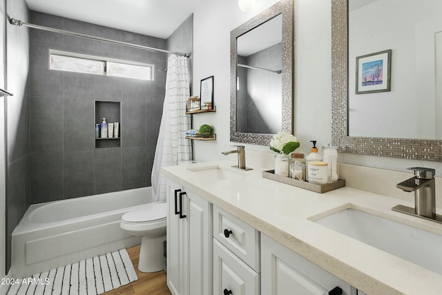 full bathroom with hardwood / wood-style floors, vanity, shower / tub combo, and toilet