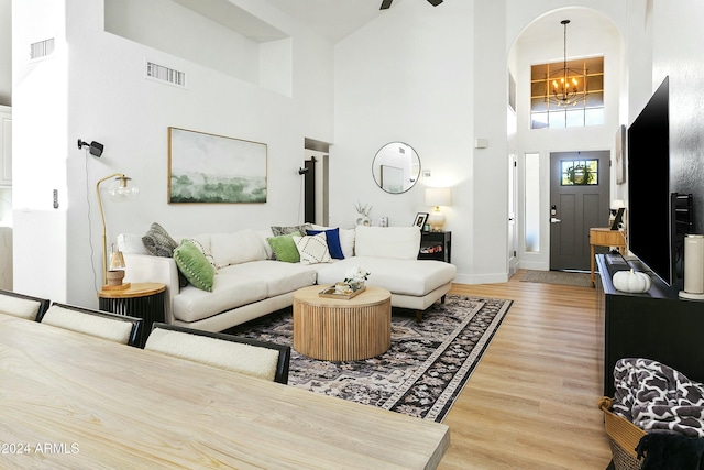 living room featuring a notable chandelier, wood-type flooring, and a high ceiling