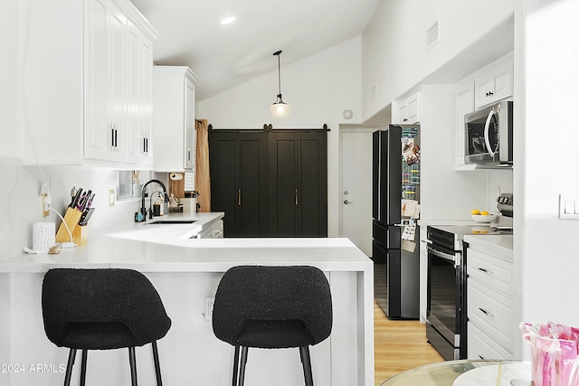 kitchen featuring a kitchen breakfast bar, kitchen peninsula, white cabinets, and stainless steel appliances